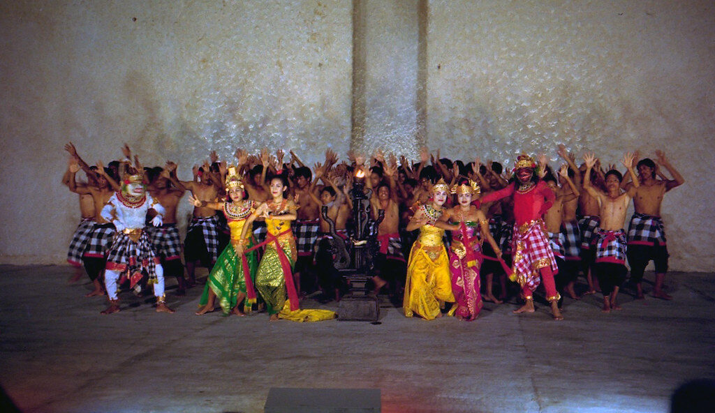 A troupe of Balinese dancers in bright ceremonial dress, lined up on stage.
