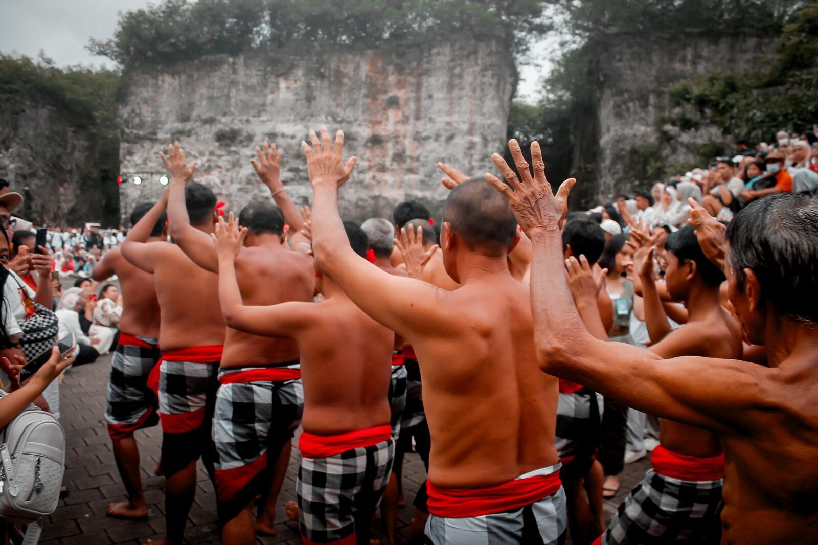 The Kecak chorus, arms flung up mid-chant — the human orchestra that carries the fire dance.