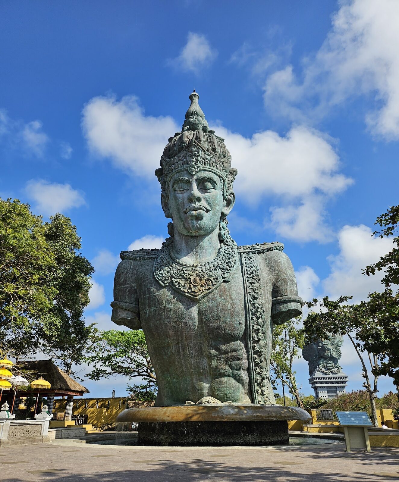 A close look at Vishnu's crowned head and torso, the copper-and-brass skin weathered pale sea-green.