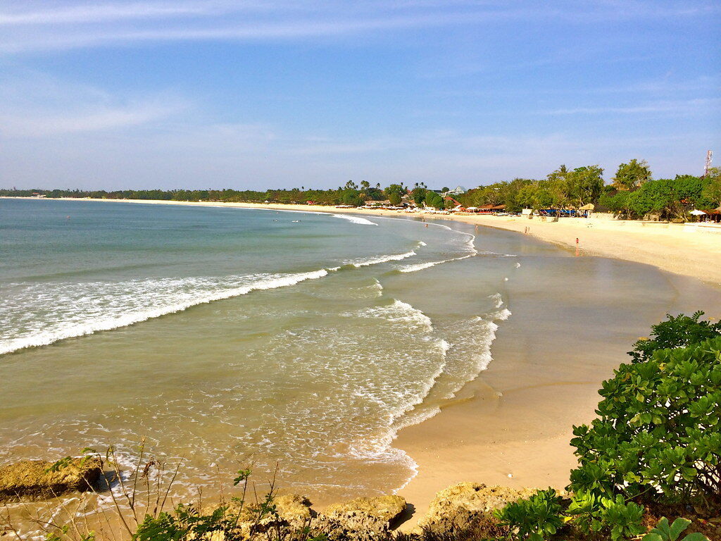The wide, calm sweep of Jimbaran's bay — broad sand and gentle water, no reef and no surf.