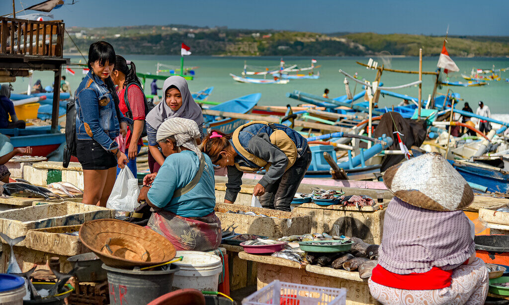 The fish market spilling onto the beach, the outrigger boats drawn up behind — the working heart of the bay.