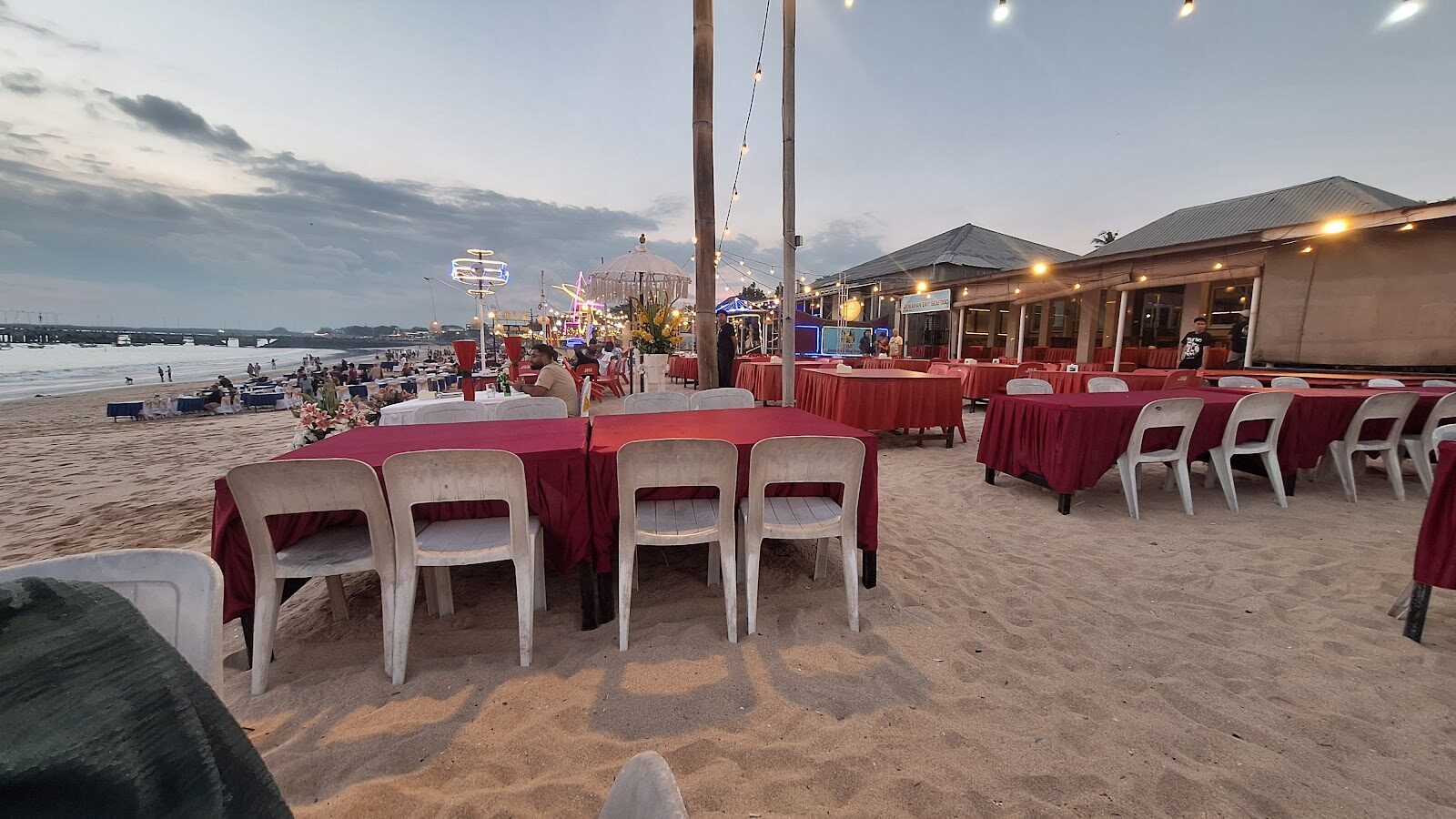 Bare tables laid out on the sand by day, waiting for the evening crowd.