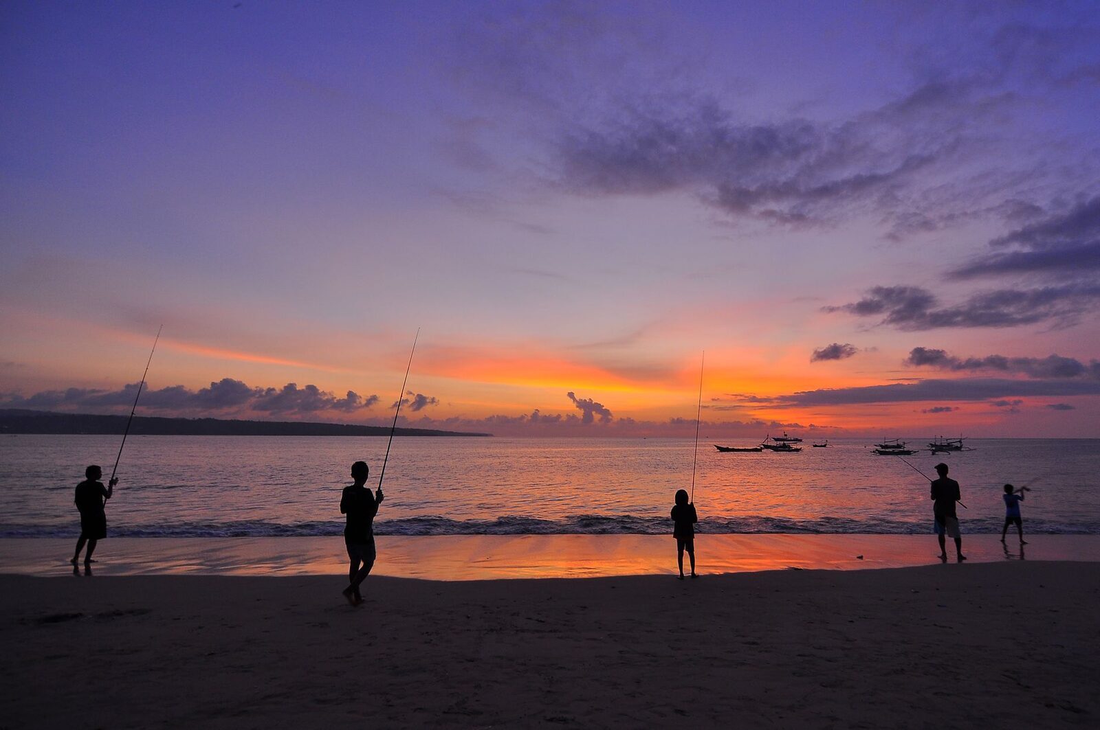 A vivid purple-and-orange dusk with figures scattered along the shore.