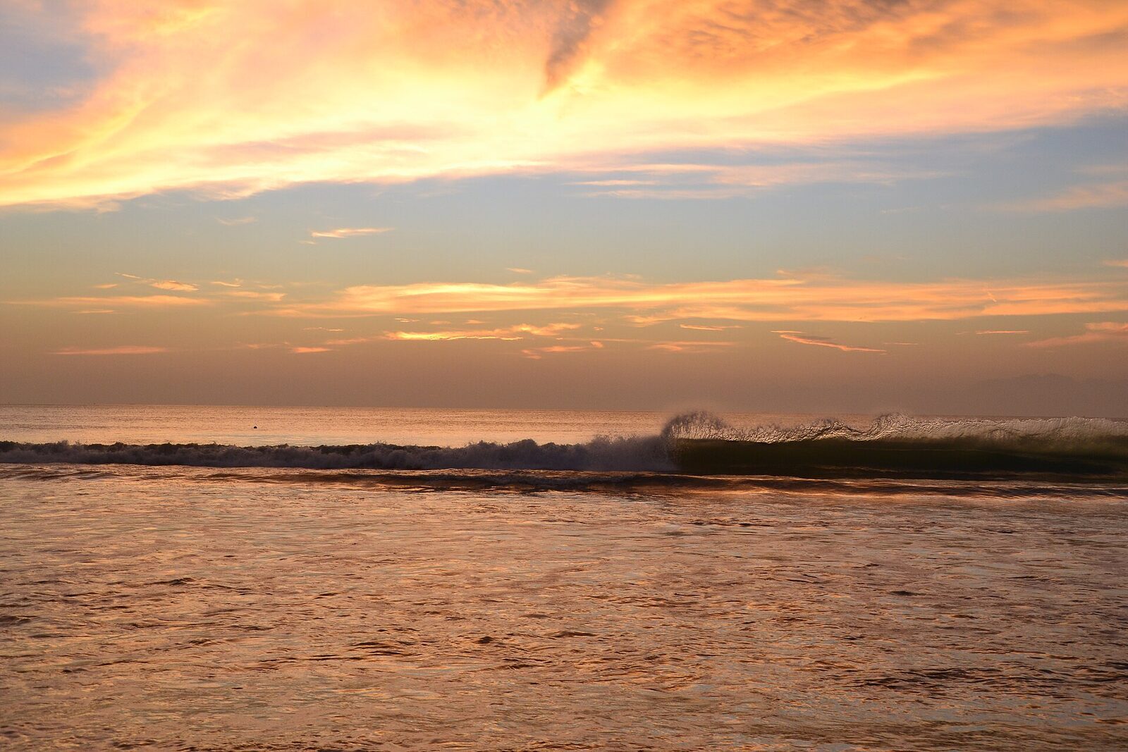 A golden sunset over the flat, calm water.