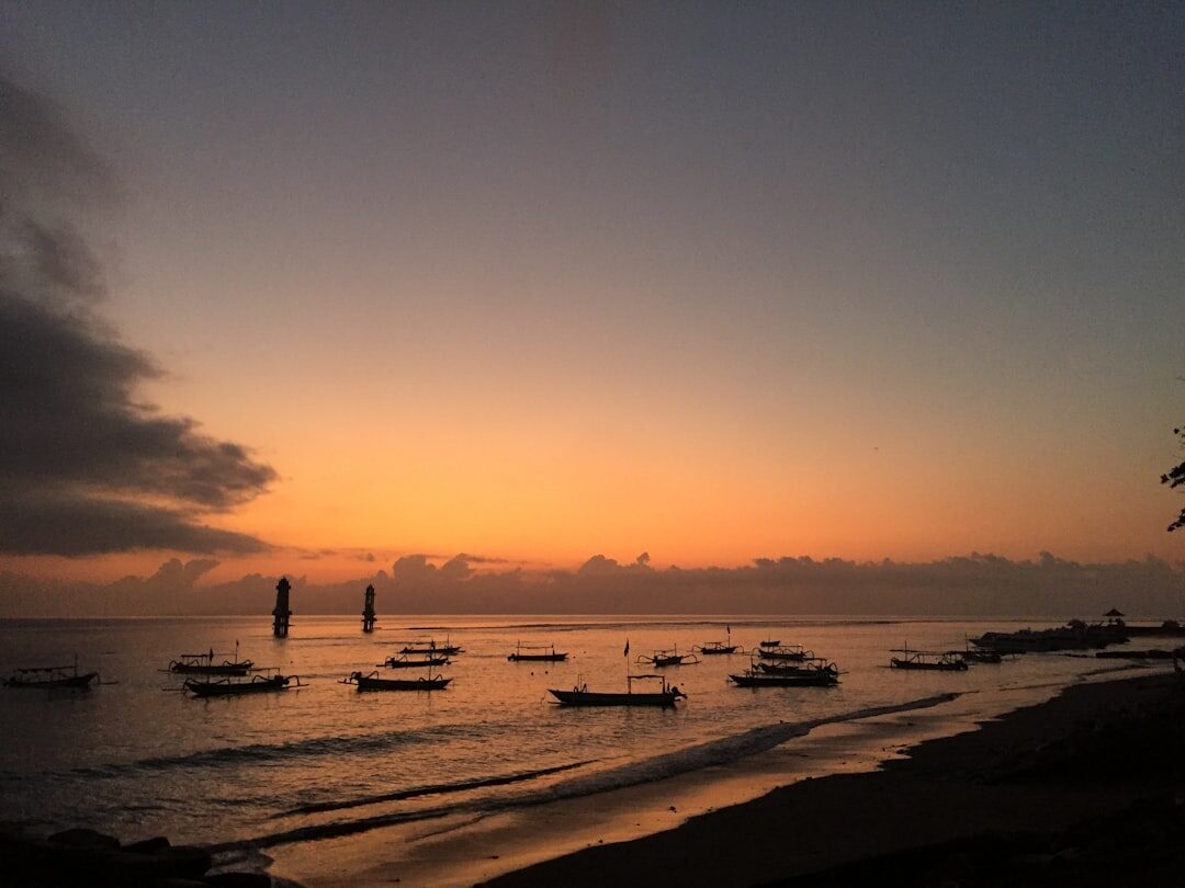 Sunset over the calm bay, fishing boats moored on the still water.
