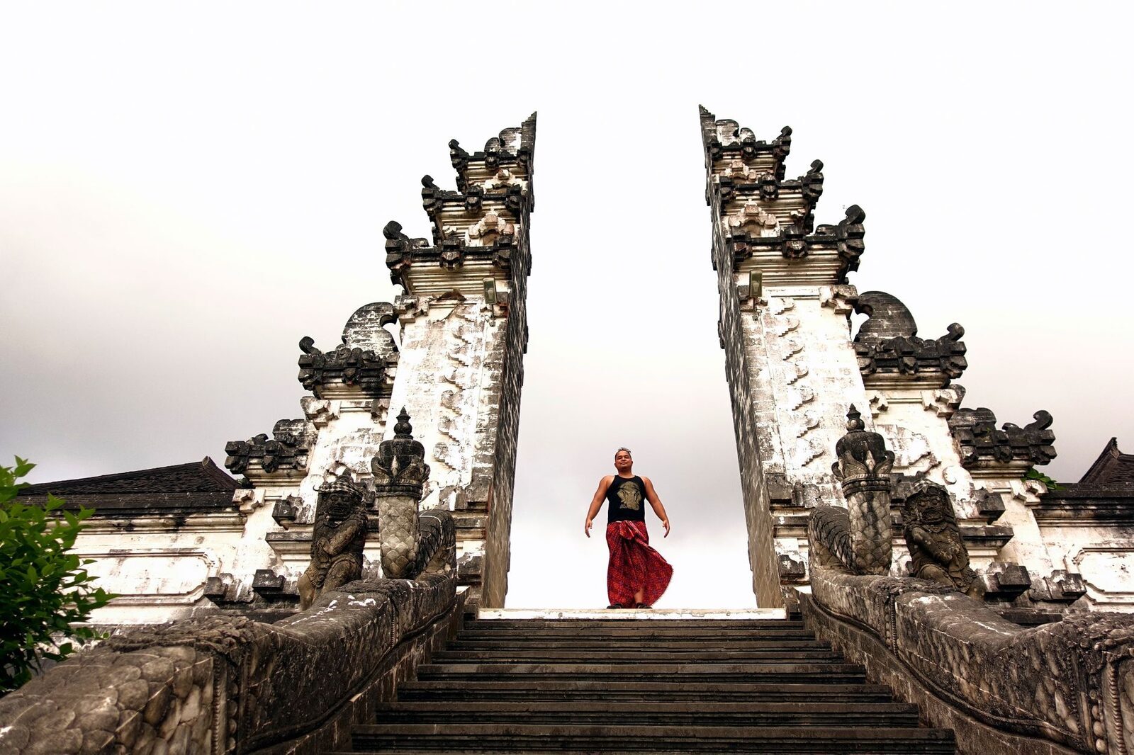A visitor in a rented sarong descends between the gate's halves after their turn.