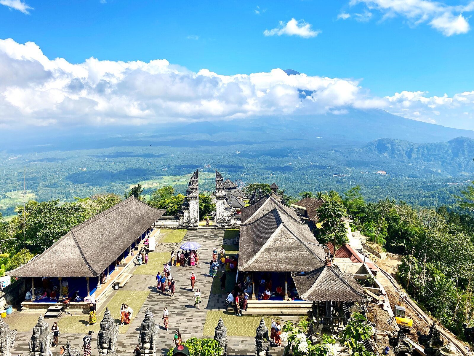 The temple courtyard at Pura Lempuyang — thatched-roof shrines and worshippers, a working temple above the viral gate.