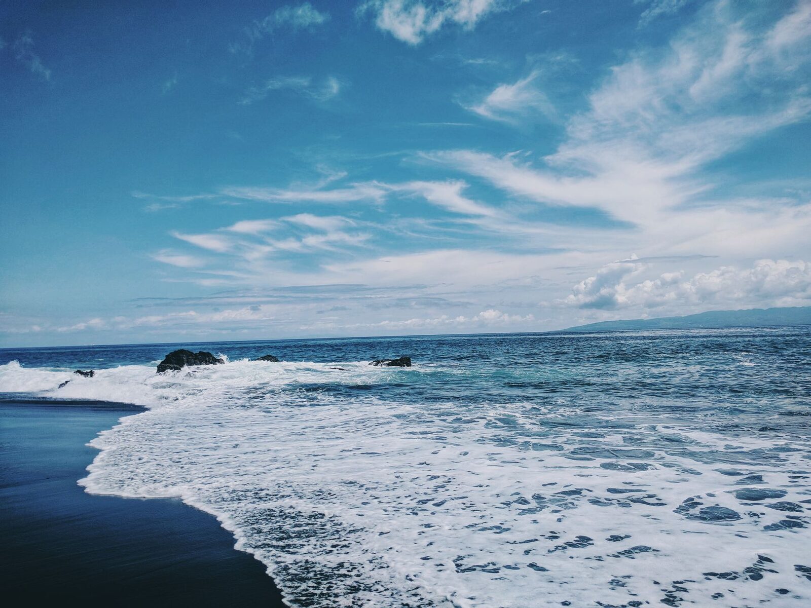 Black sand against blue water — pretty in its own way, just not the turquoise-and-gold most people picture.