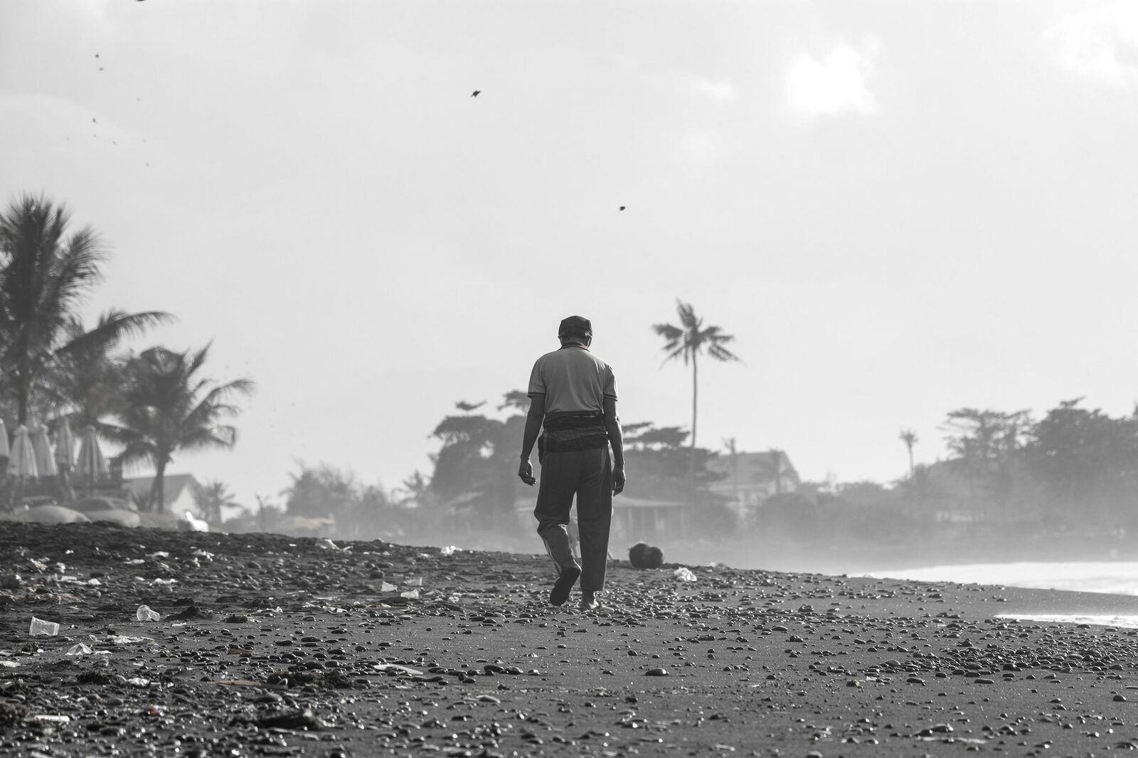 Bali's sand up here is grey-black volcanic, not golden — a working, faded-town shore rather than a postcard beach.