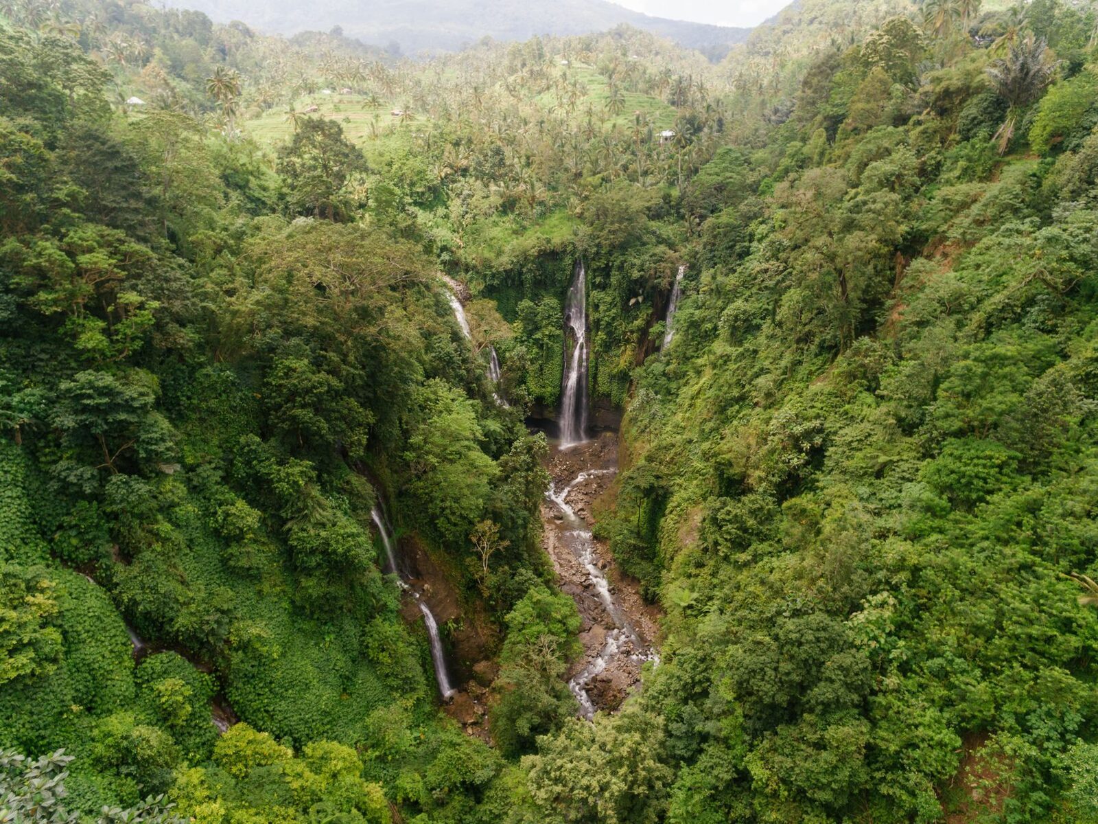 Aerial over a north-Bali cascade — the kind of jungle waterfall the Sekumpul loop strings together. (A north-Bali waterfall.)