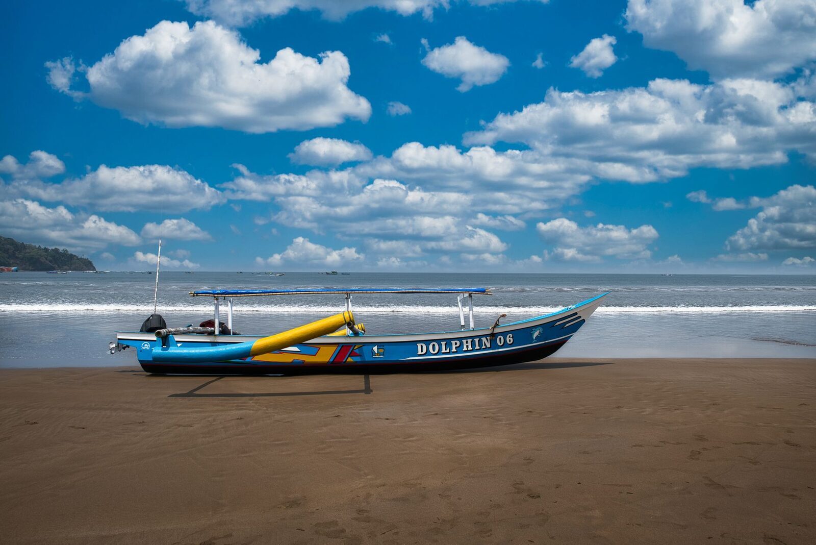 A dolphin-tour outrigger pulled up on the black sand — the small jukung boats that run the sunrise trips.