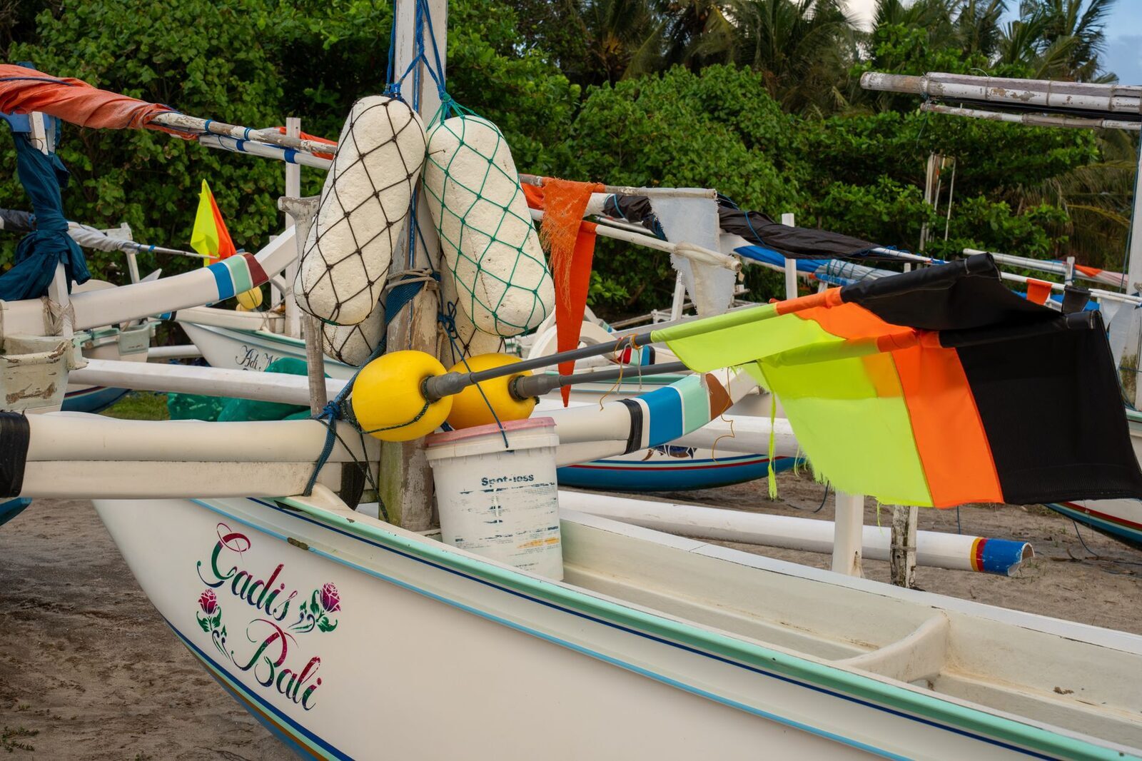 A traditional outrigger rigged with flags — the same style of boat used for the dolphin runs. (A Bali jukung.)