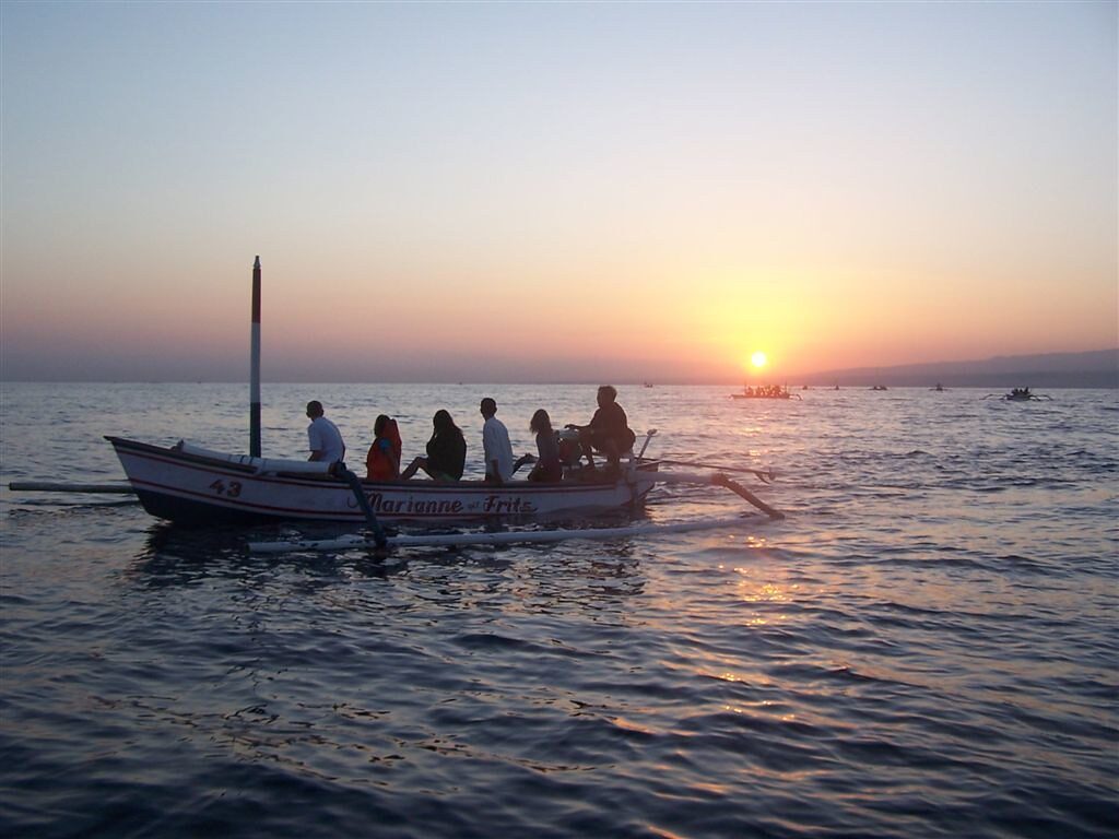A dawn dolphin boat heading out over glassy water — on a calm morning this half is genuinely lovely.