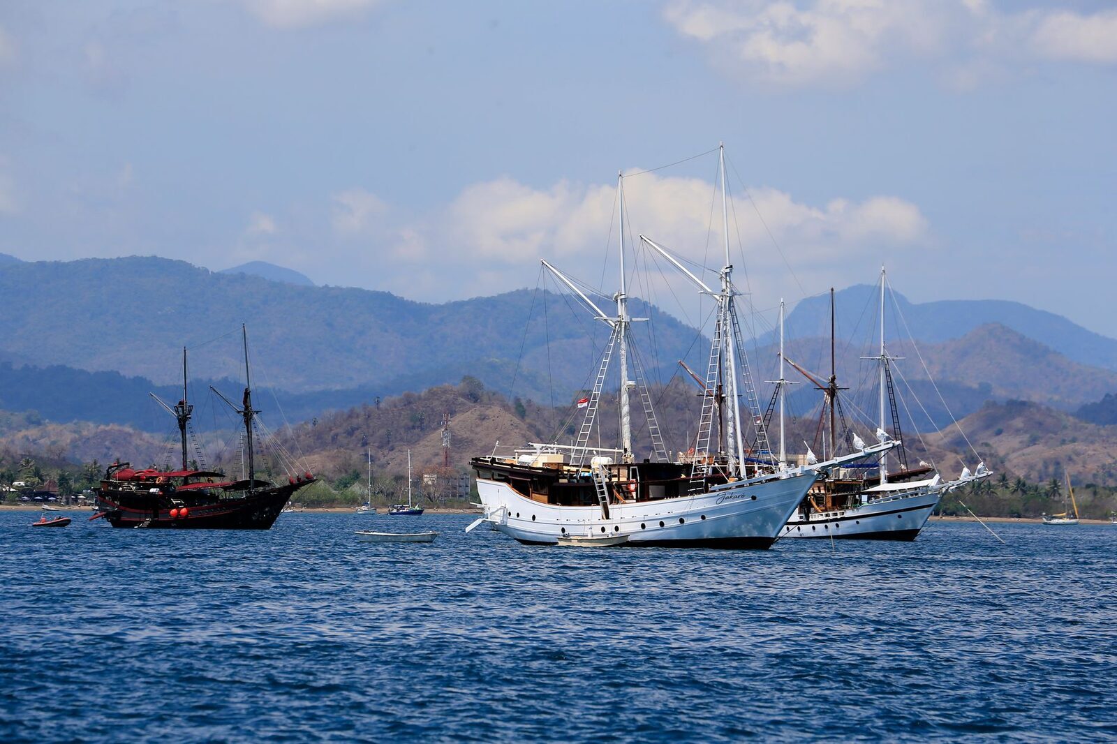 Wooden boats moored in the still bay below the north-coast hills.