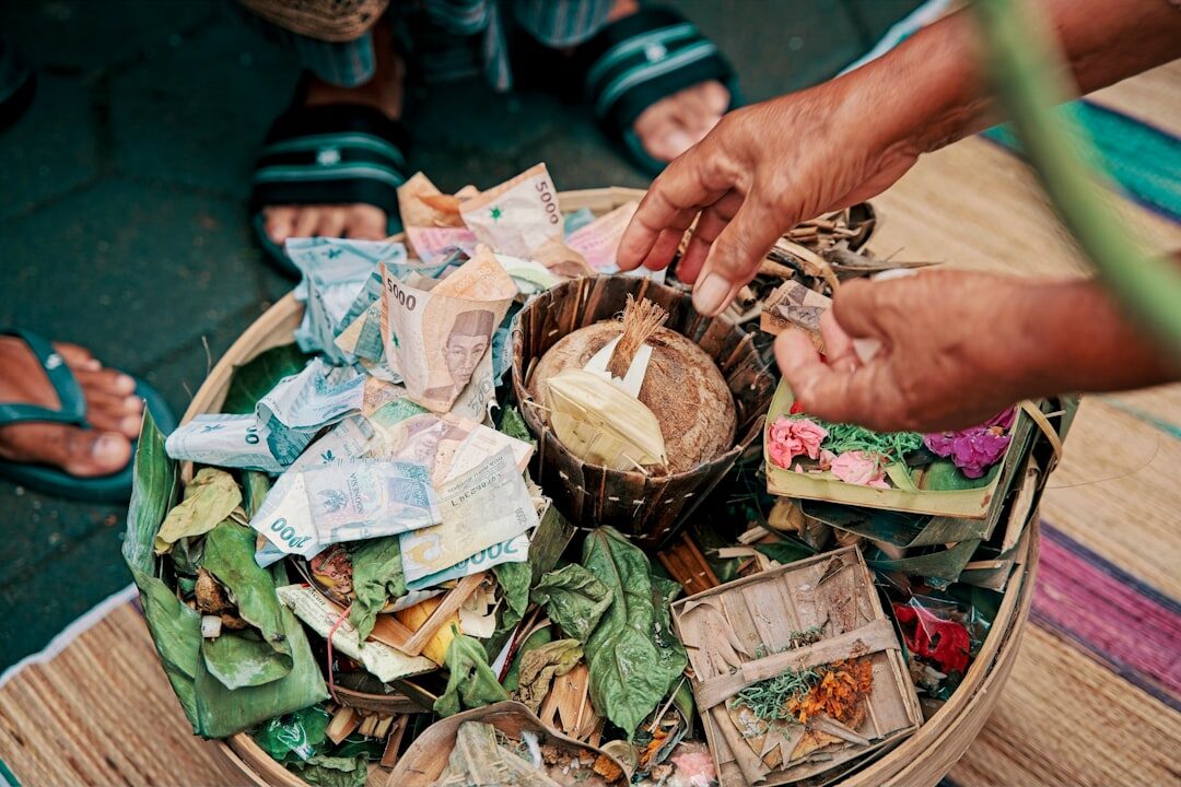 Cash changing hands at a market — the warung, pasar and roadside economy runs on paper only. Food and a room are cheap; it's the drivers, tours and entrance fees that quietly add up.