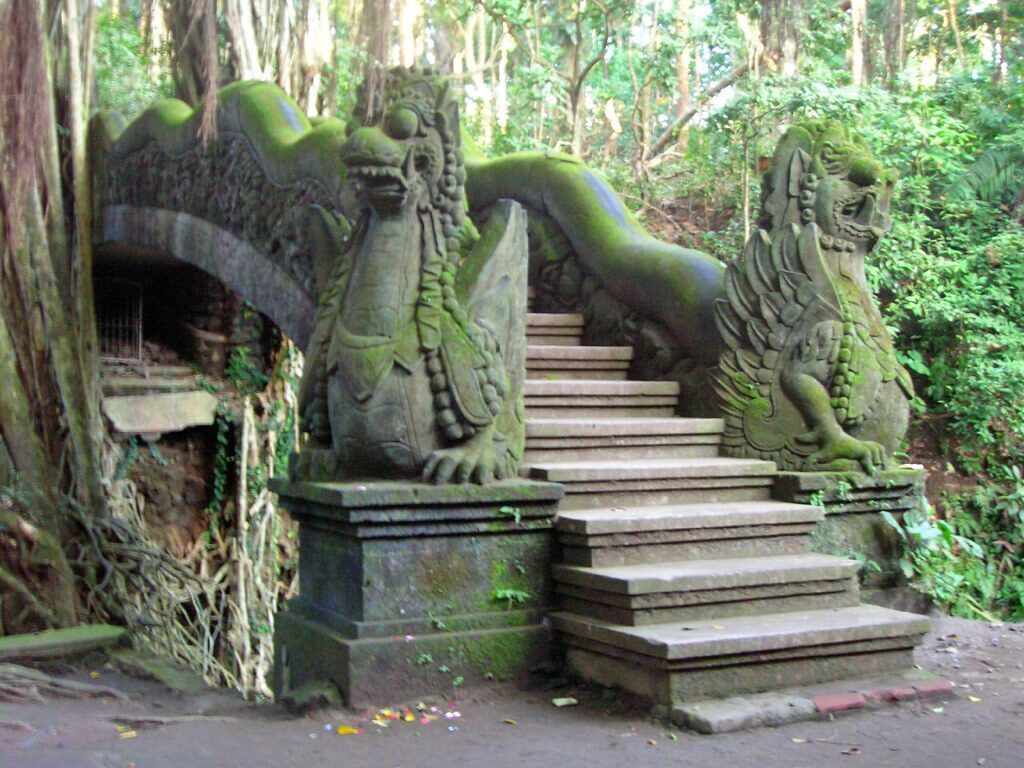 A dragon-carved staircase flanked by guardian statues, greened with moss.