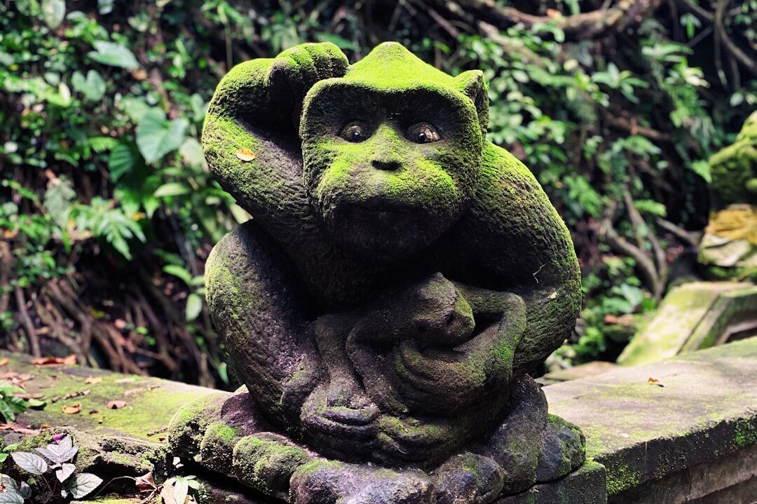 A carved figure slowly disappearing under moss in the damp forest air.