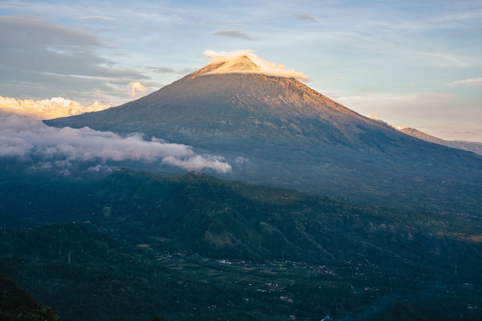The cone catching the first sun above a collar of cloud.