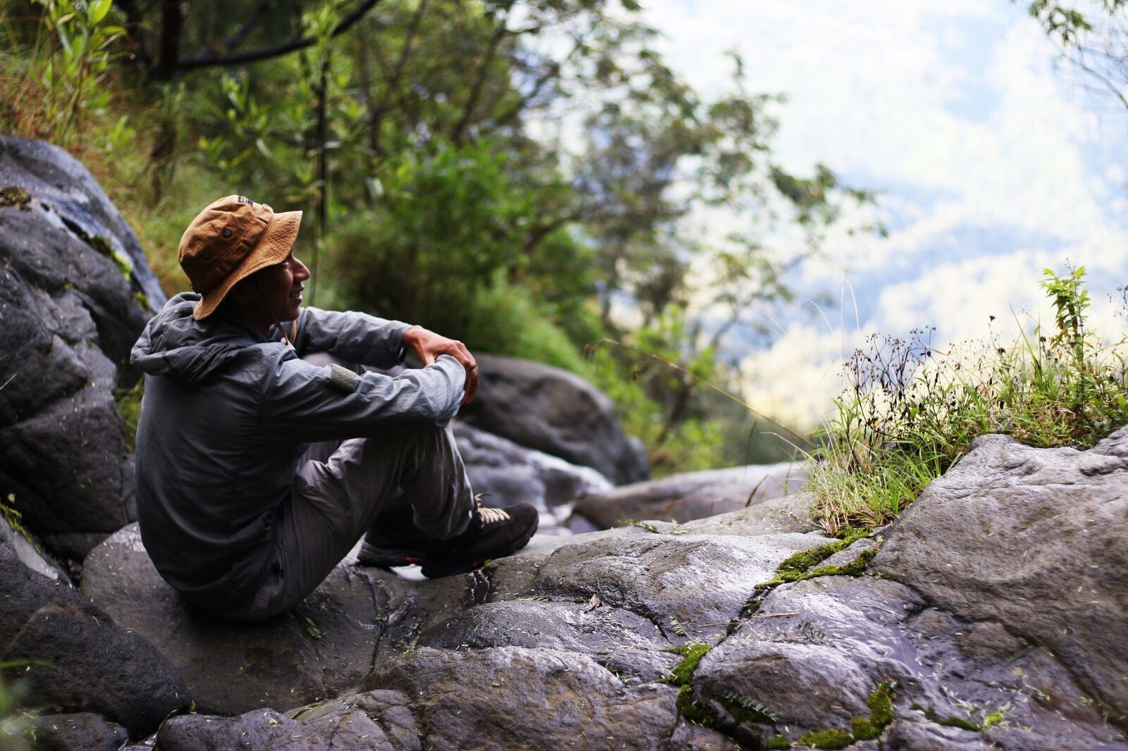 A trekker resting on the rocks partway up; much of the Agung climb is steep and hands-on.