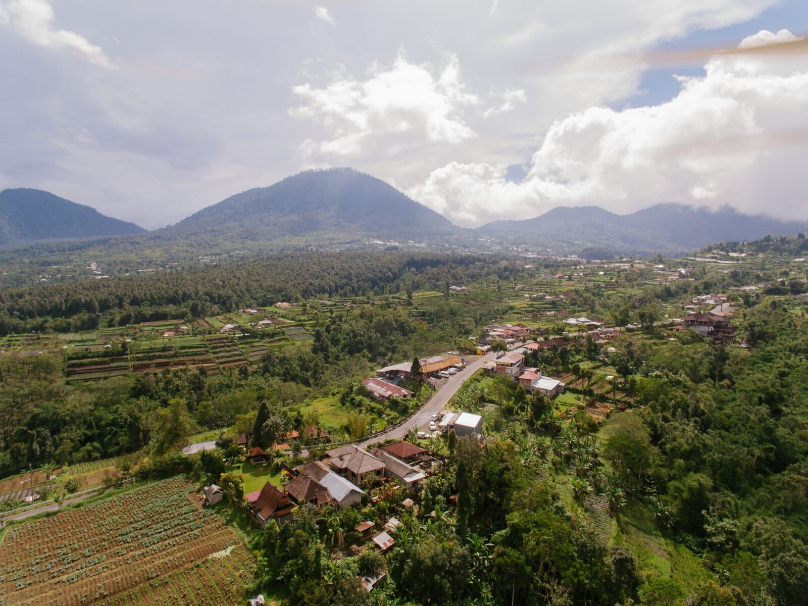 A highland village tucked below the north-Bali volcanoes, fields running up to the tree line.