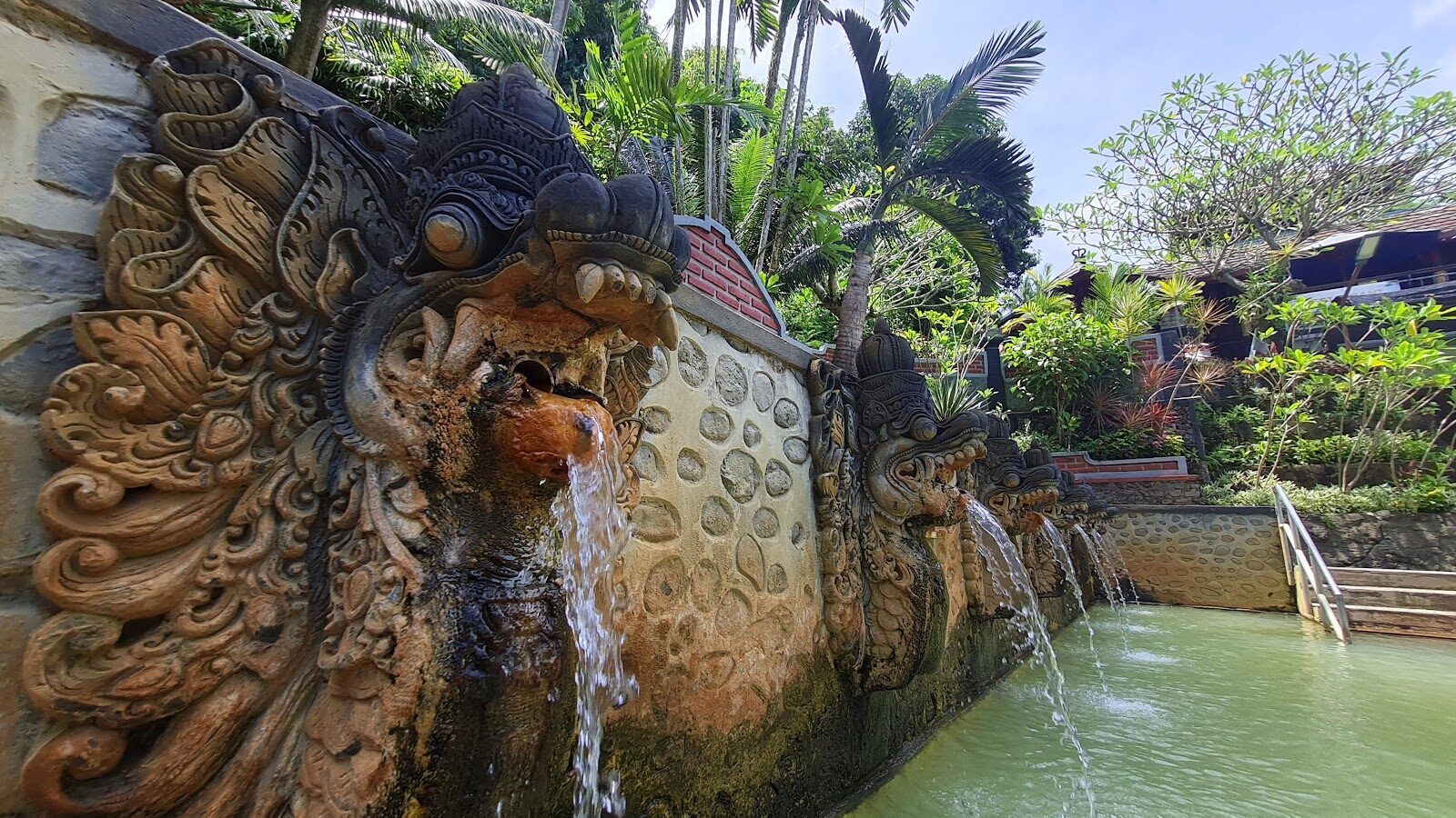 The carved stone naga spouts of the Banjar hot springs, pouring warm sulphur water into garden pools — the signature stop west of Lovina.