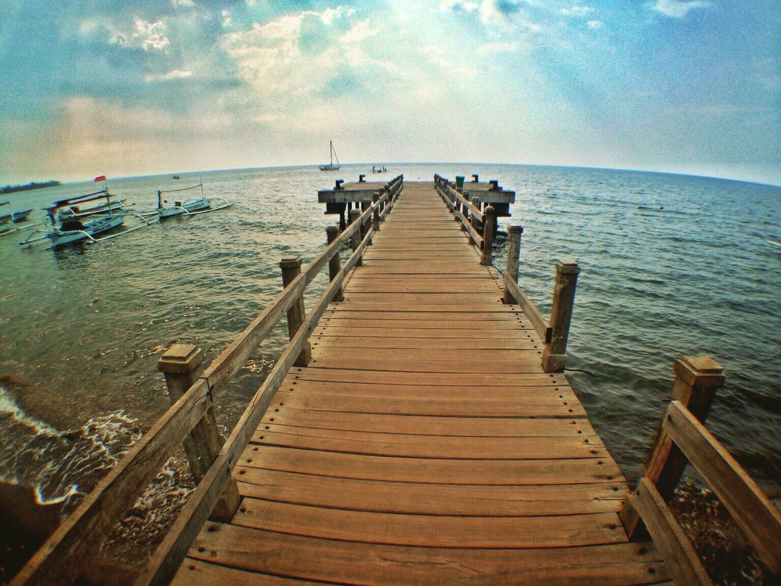 A wooden jetty over calm water on the quiet north coast — the snorkel-and-slow-down side of Lovina.