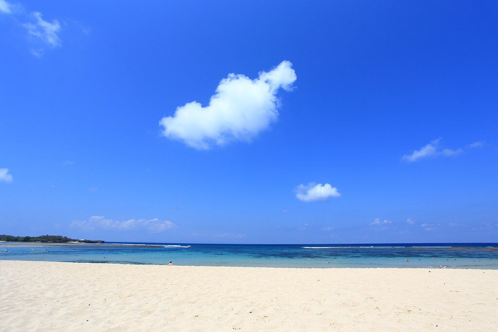 Clean white sand and still water under a clear sky.