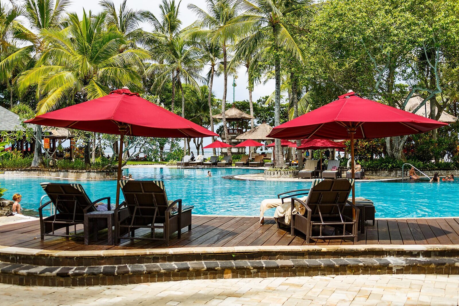 A resort pool under red umbrellas — the flop-and-drop the enclave does well.