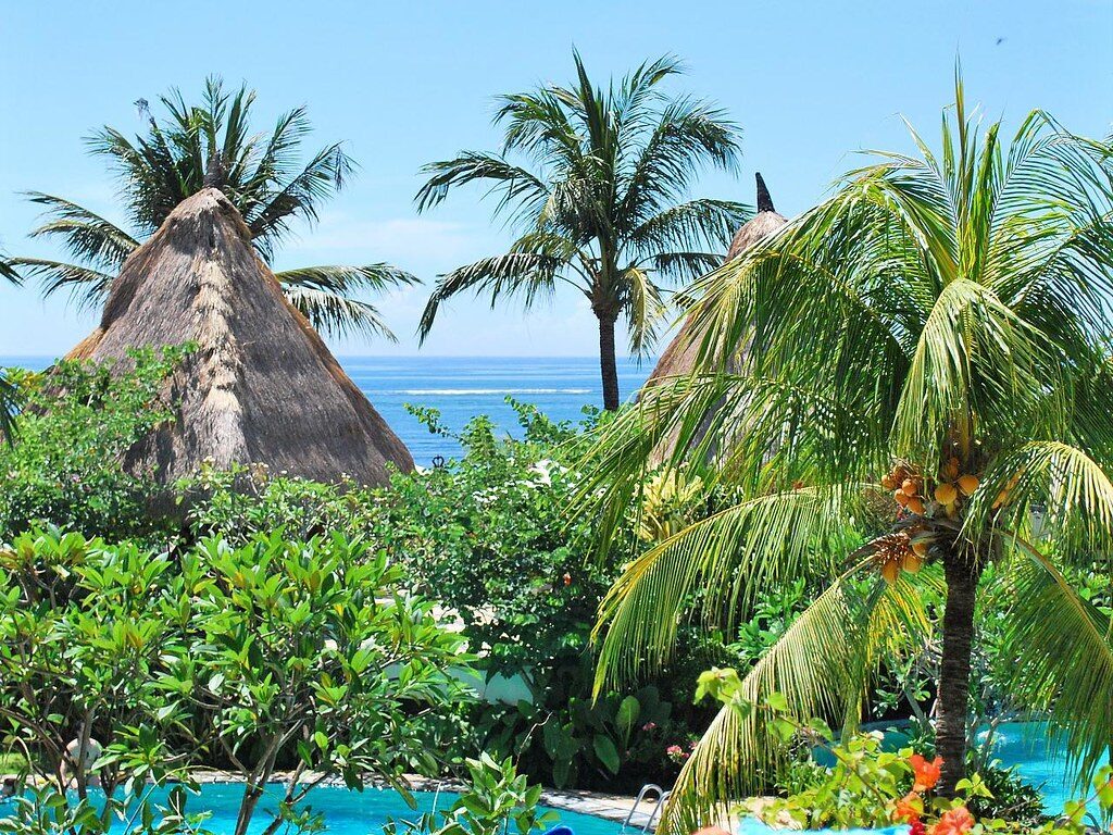 Thatched pavilions and palms around a hotel pool inside the gates.
