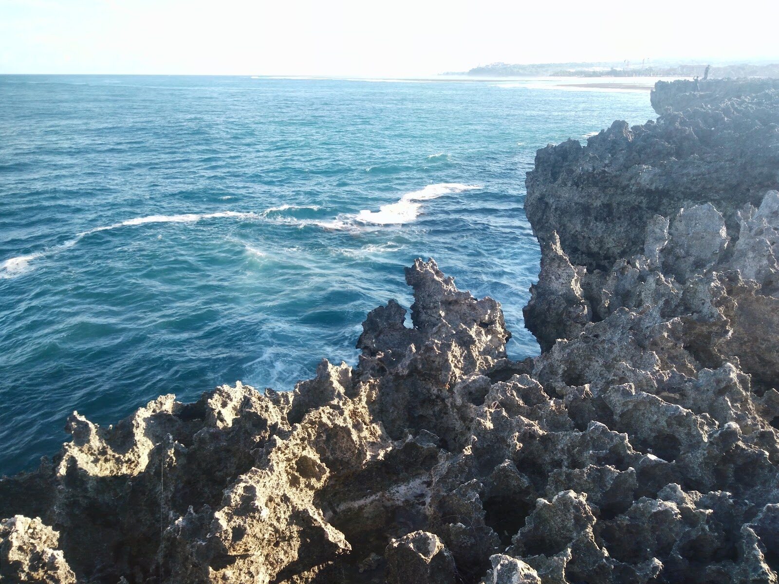 The jagged rock point the swells hit — dramatic in surf, flat and underwhelming when the sea is calm.