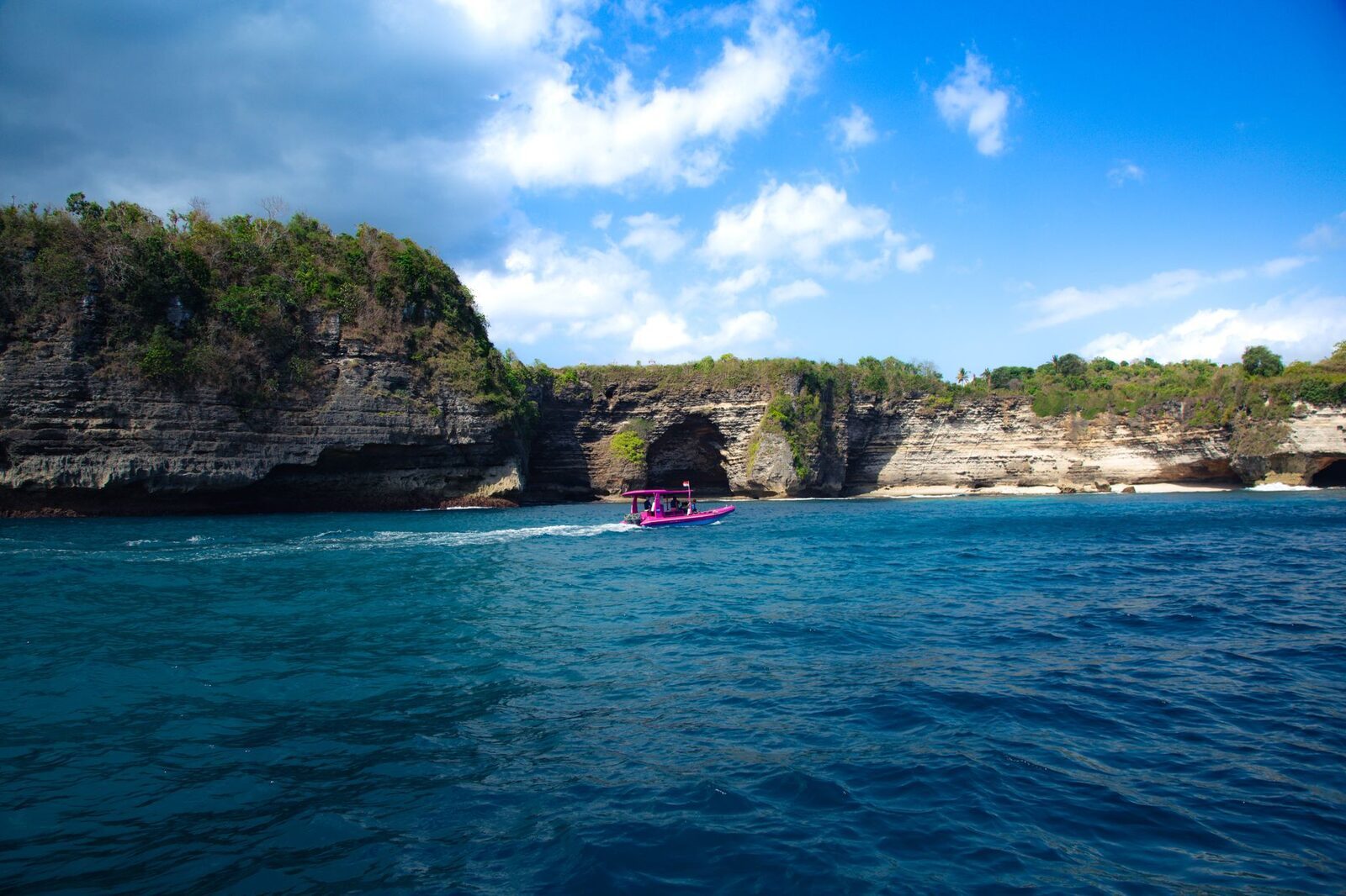 A speedboat running past the cliffs on the crossing to the Nusas.