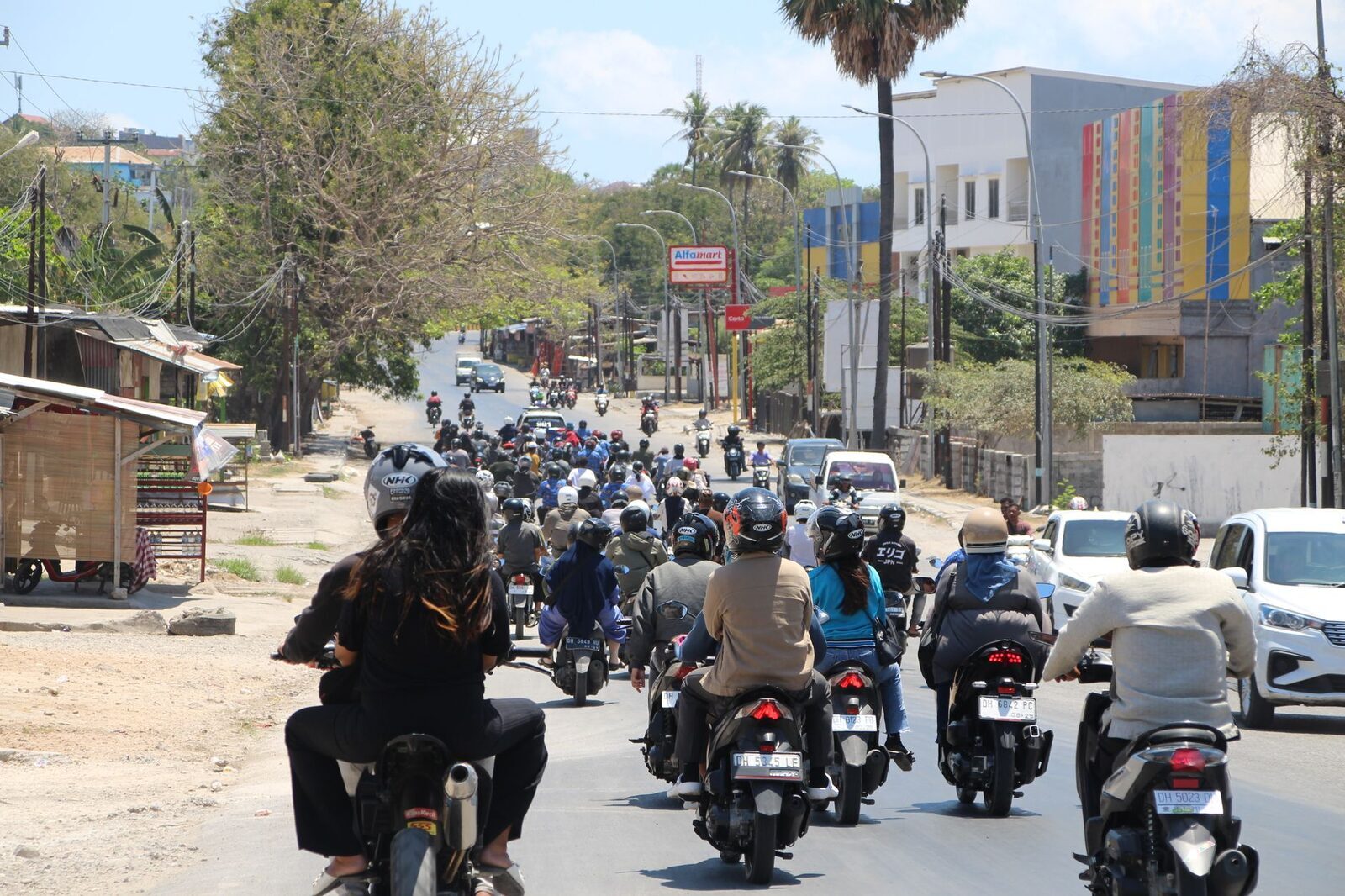 A road choked with scooters and cars — the pinch points get busy when day-tour traffic lands.