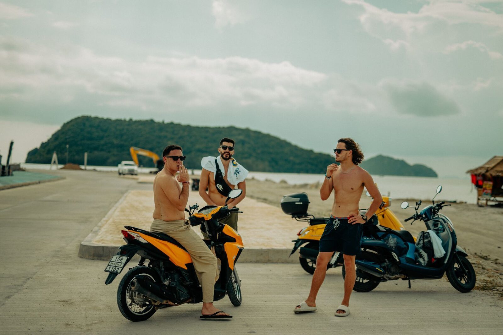 Travellers with hired scooters at a Nusa Penida viewpoint — cheap to rent, genuinely dangerous on the island's roads if you're not a confident rider.