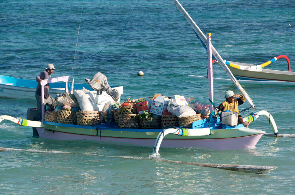 A traditional jukung loaded with cargo, working the channel.