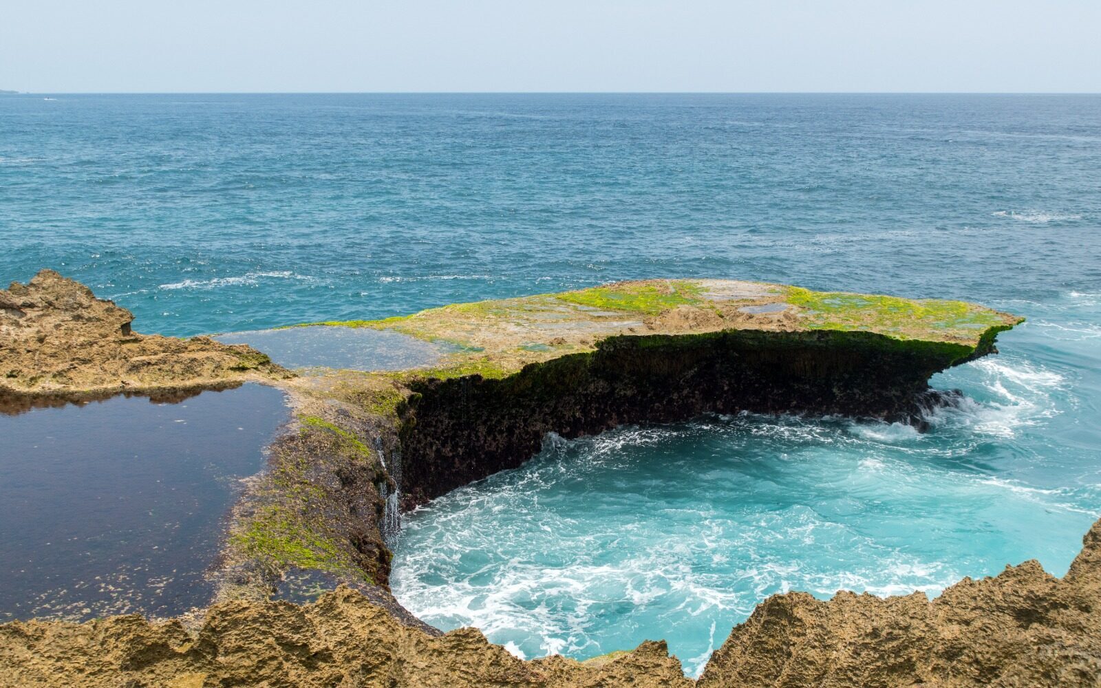 A tidal pool and blowhole on the Devil's Tear rock shelf, the open sea just beyond.