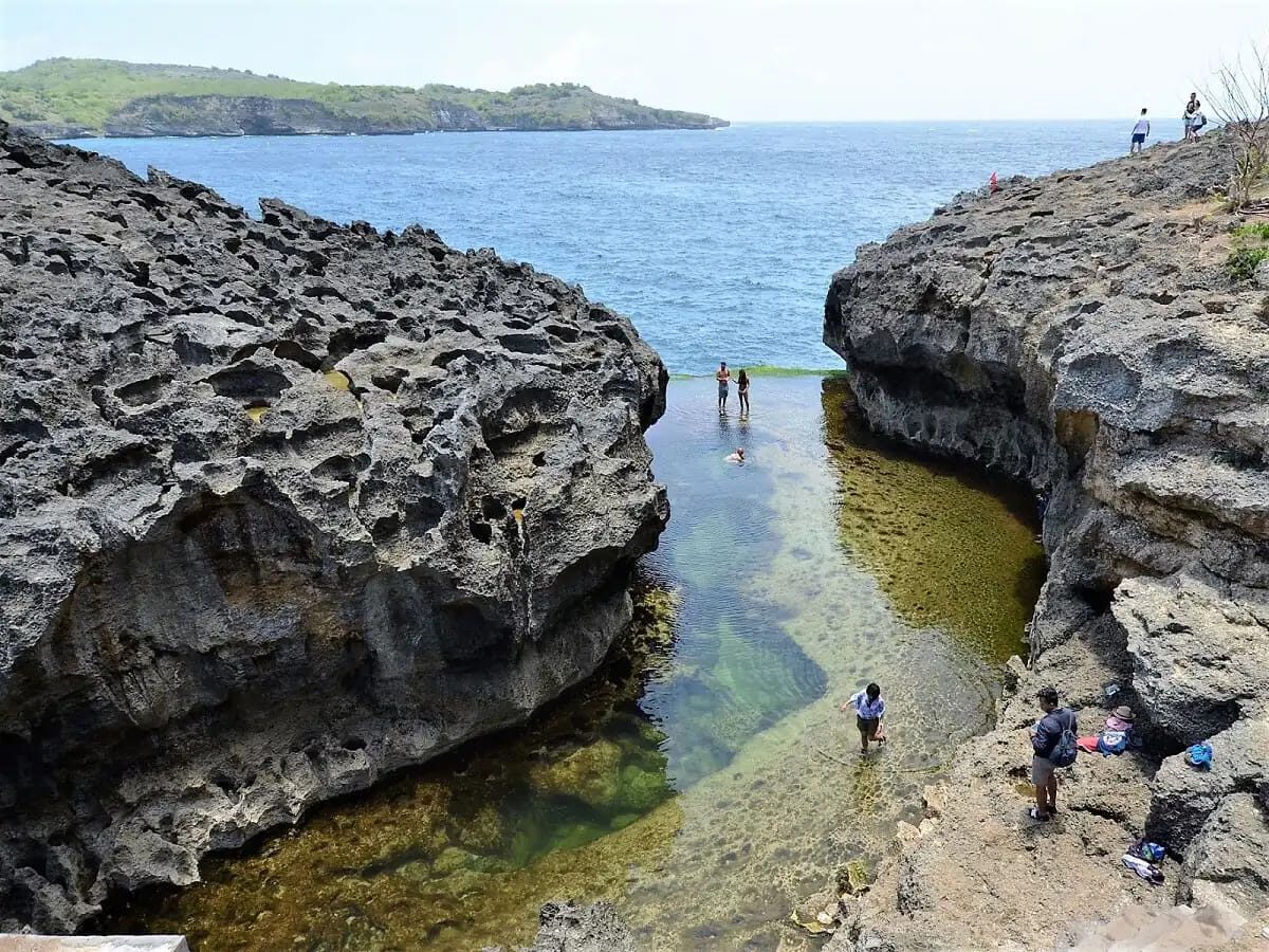 Visitors picking their way around Angel's Billabong at low tide.