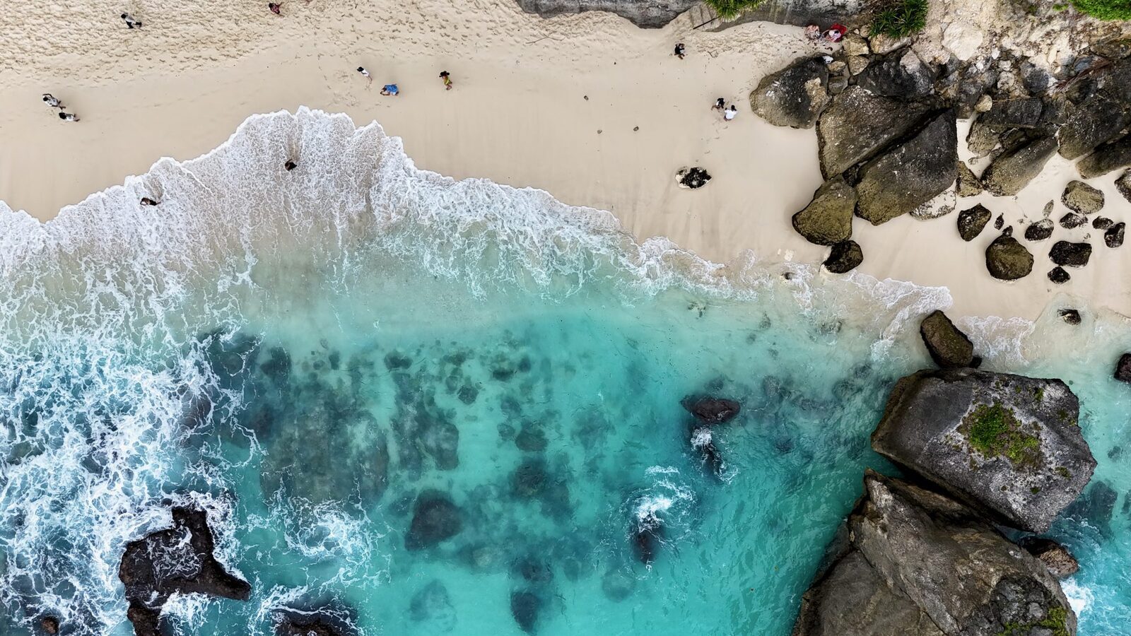 Diamond Beach from above, surf breaking white across the sand.