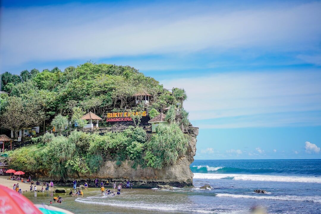 Warungs and guesthouses built into the Bingin cliff, the beach and umbrellas below.
