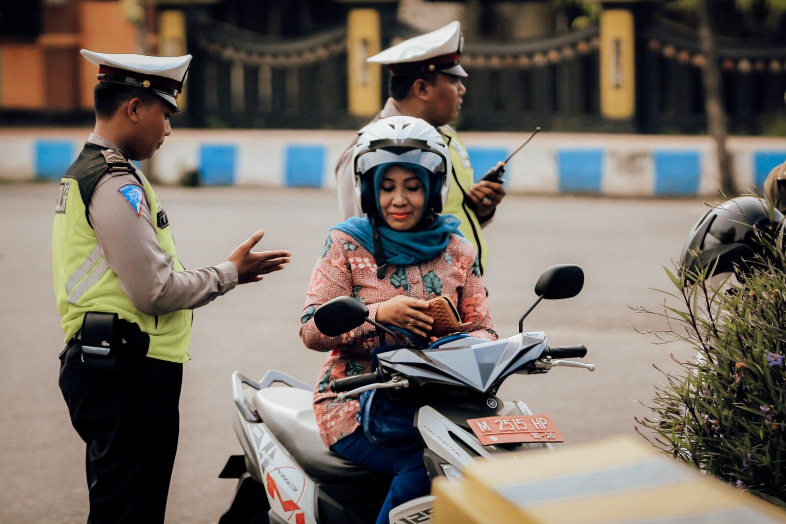 A traffic officer stops a scooter rider at the roadside — licence and helmet are what they check.