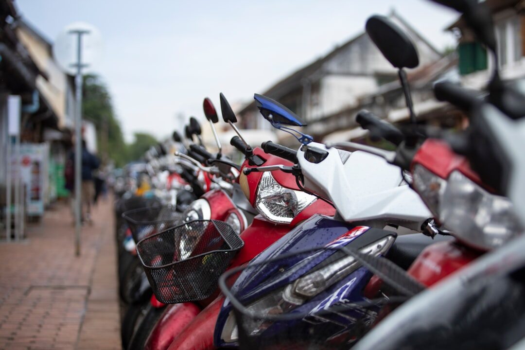 A long row of scooters parked nose-out along a street — the standard island runabouts you rent by the day.