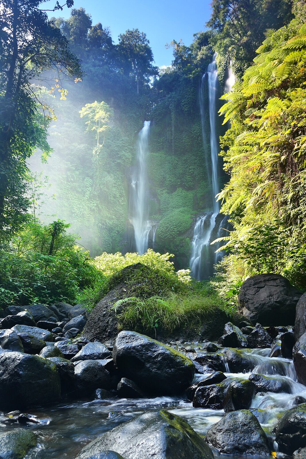 Sunlight cutting through the spray as the falls drop into the gorge.