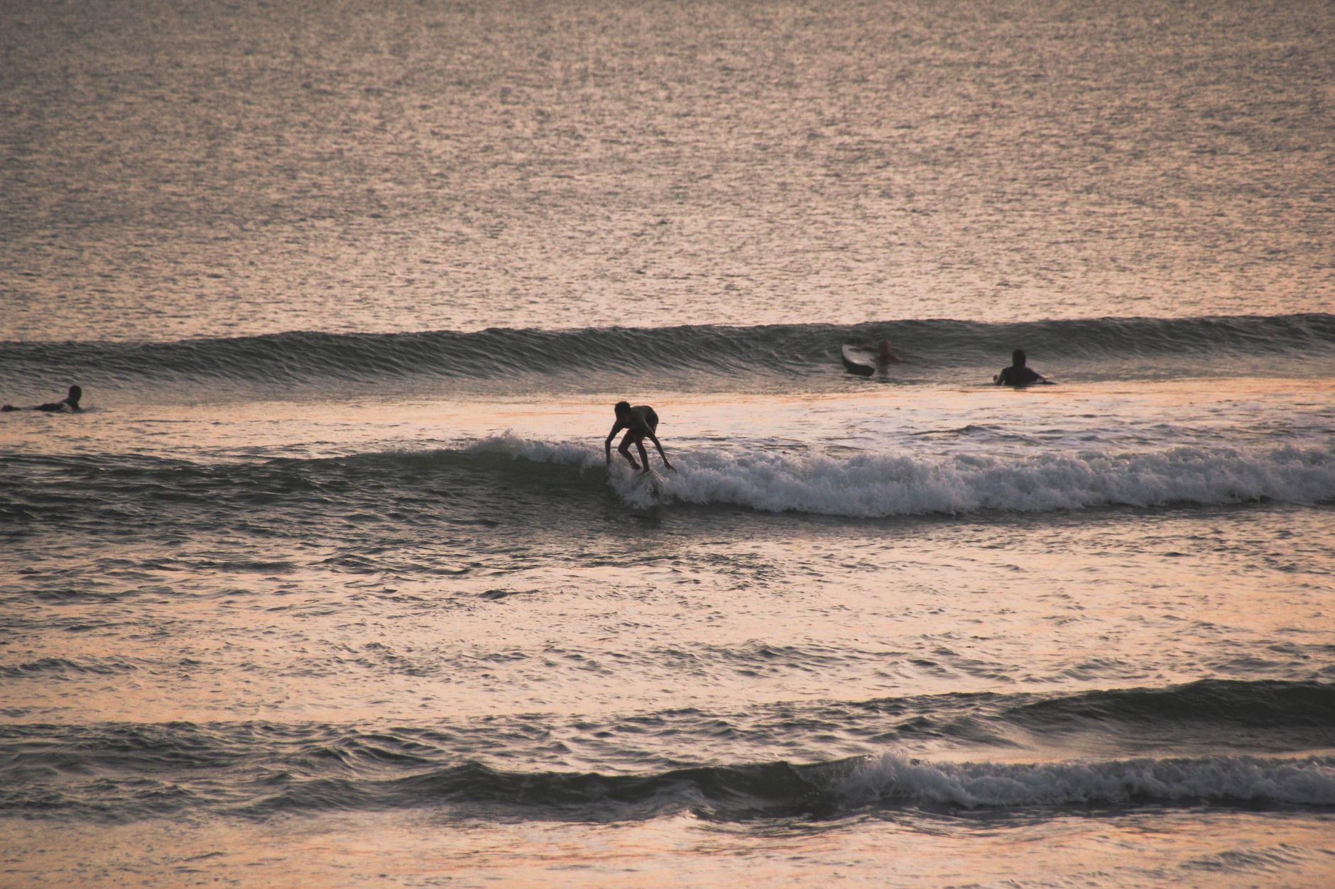 A surfer riding the waves at a Seminyak sunset