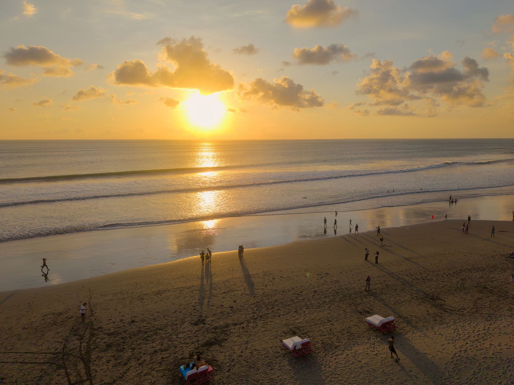 A glowing sunset over Seminyak beach with people