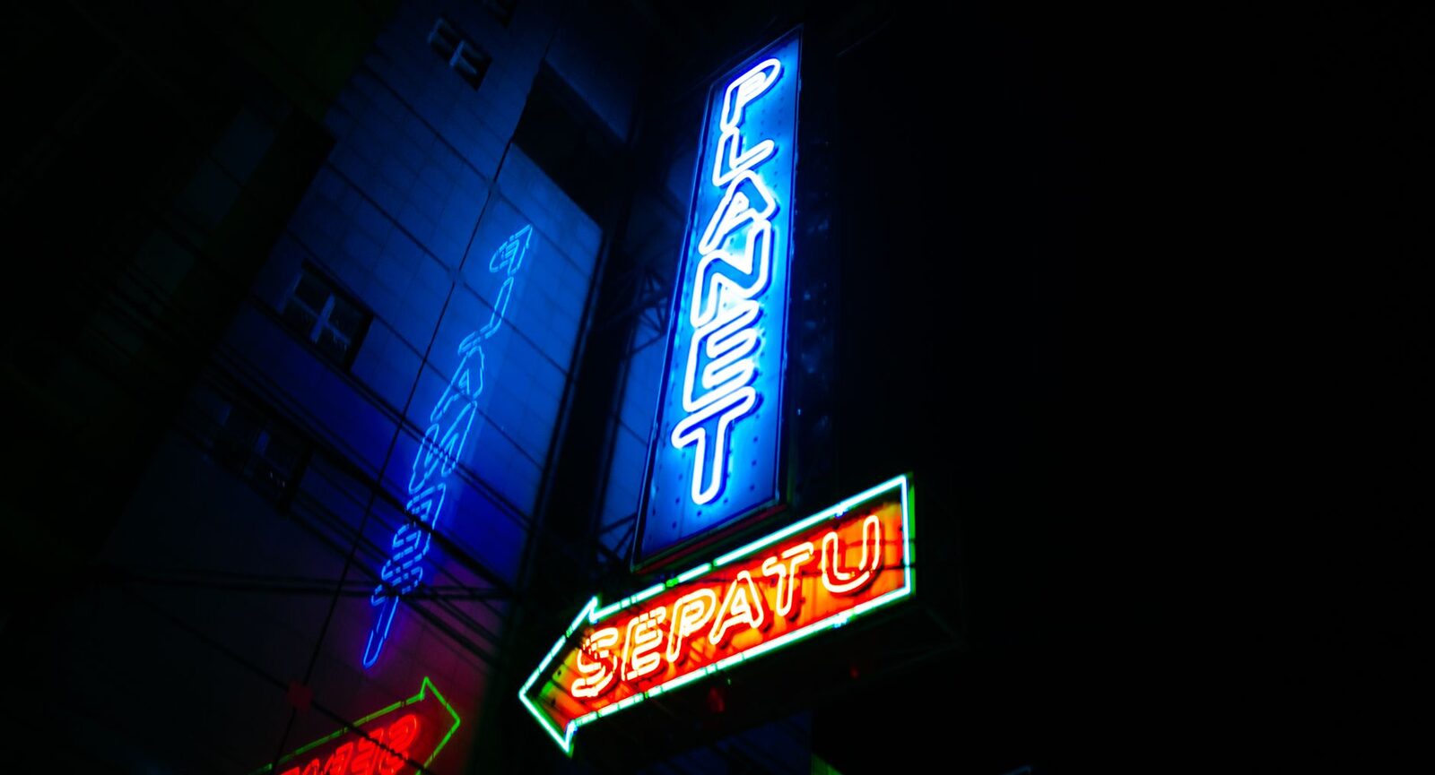 Neon signs stacked over a night street — the glow the after-dark economy runs on.