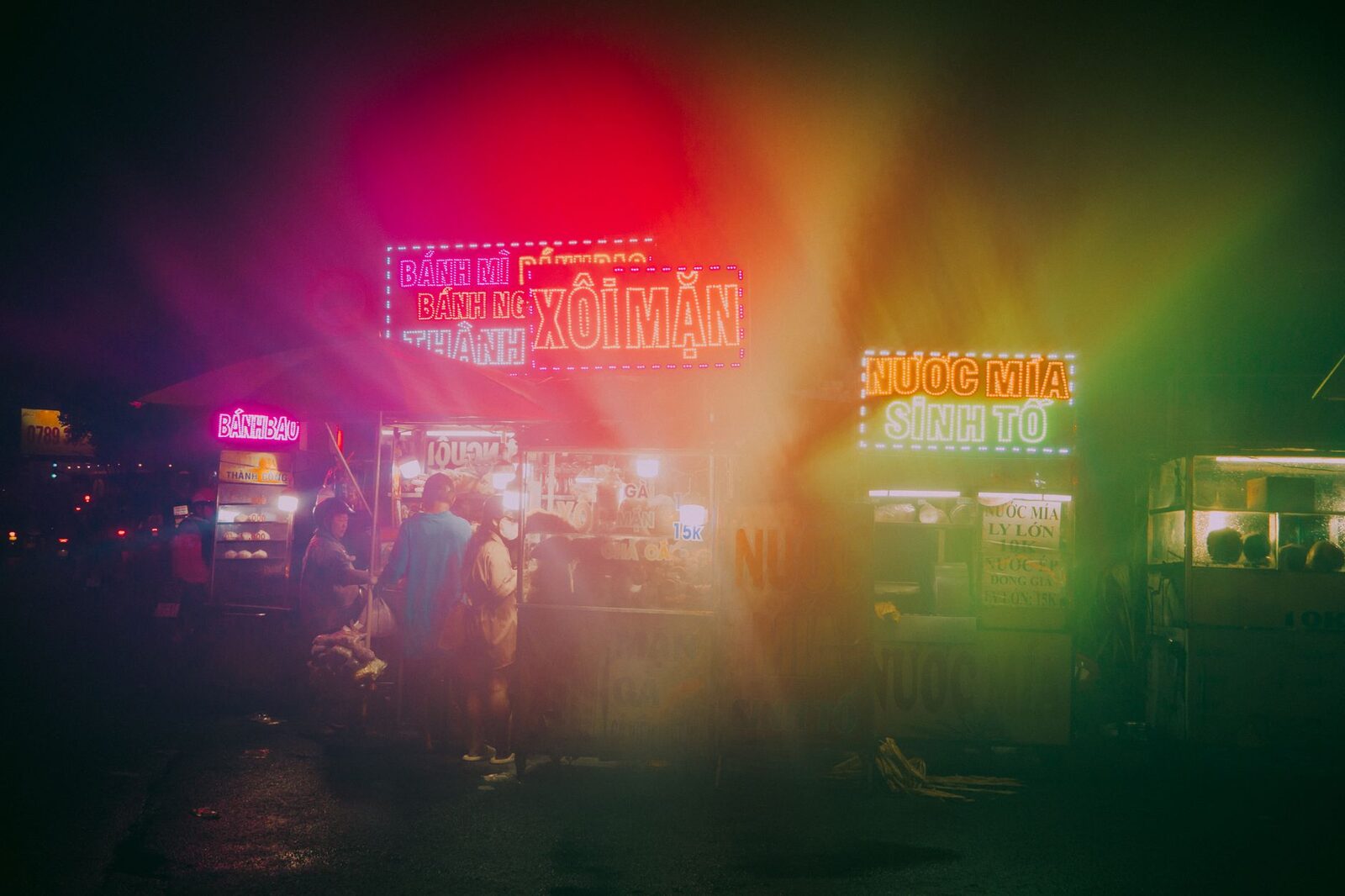 A hazy night street of stalls and coloured light.