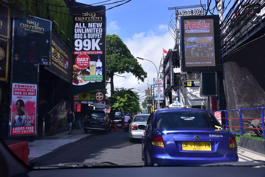 The Legian nightlife strip after dark — neon, bar-and-buffet signage, the crowd. The going-out heart of south Bali, and where the freelance scene is most visible.
