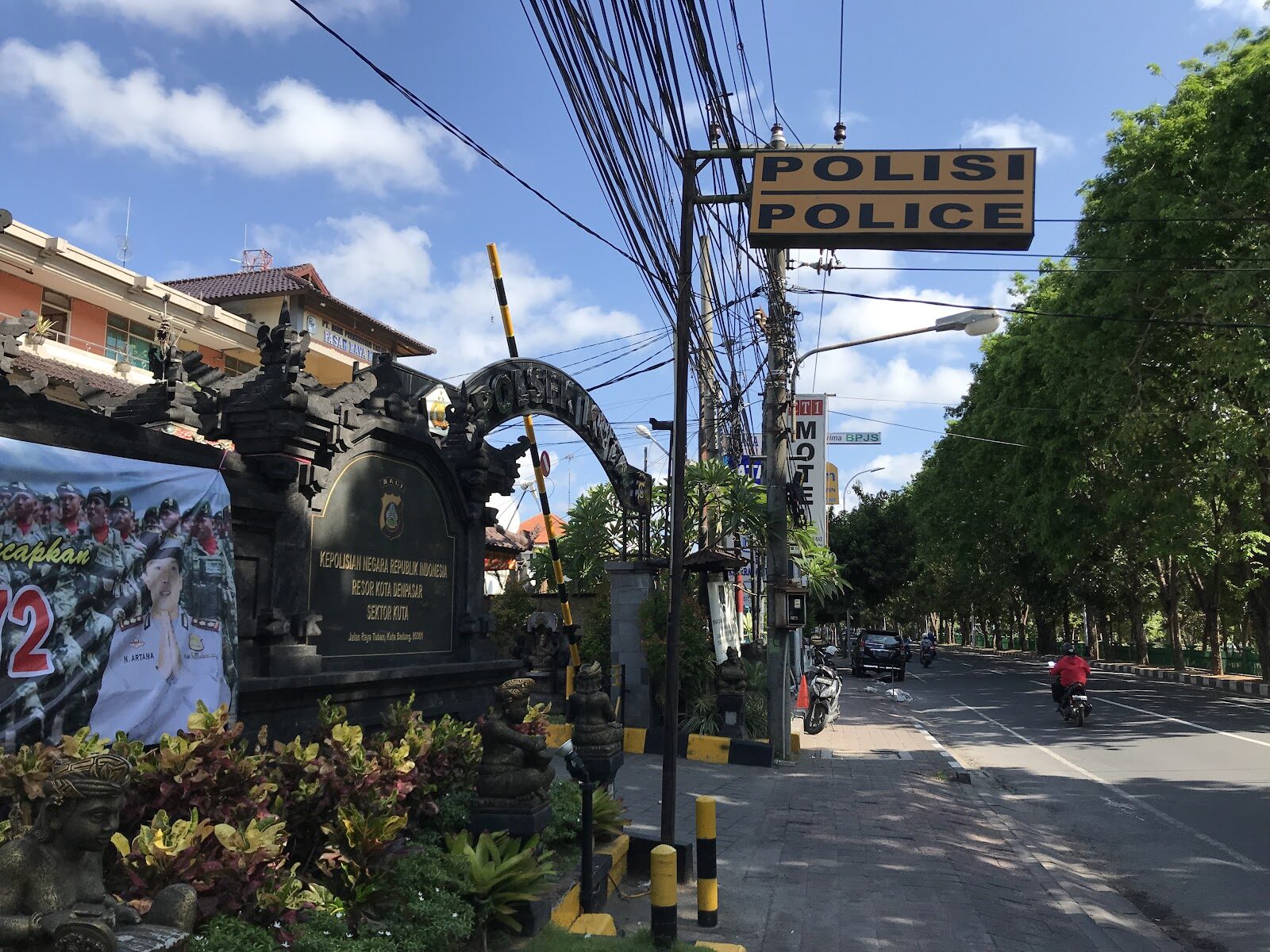 A Balinese police post — 'POLISI' on the sign, a temple gate beside it. The law is never far, even in the nightlife.