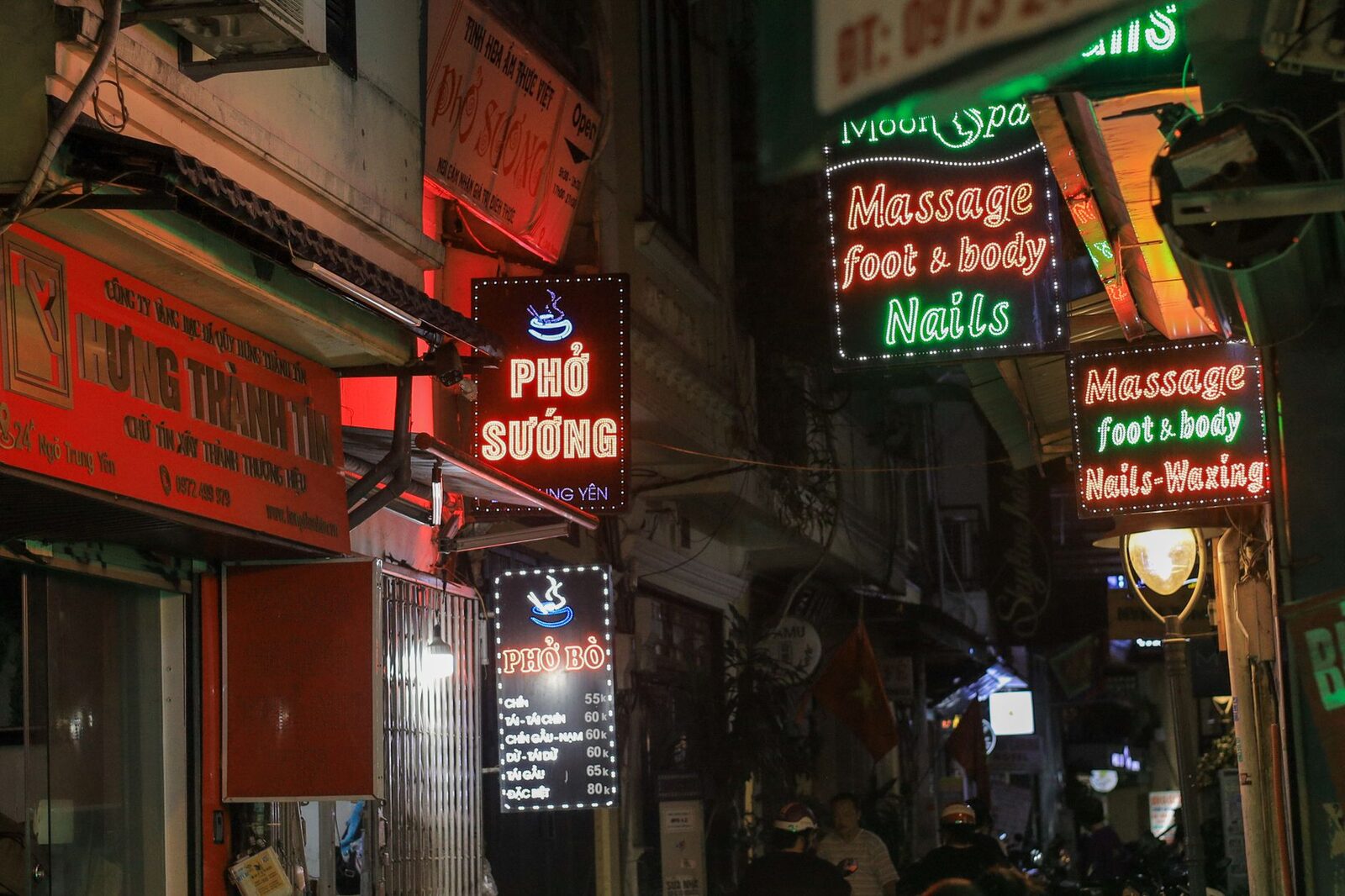 Stacked 'massage / foot & body' neon on a night street — signage, not a verdict on any one place.