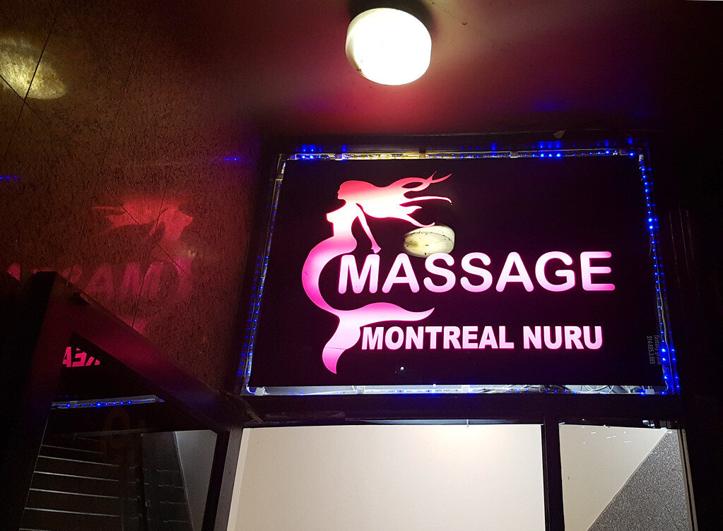 A late-night 'massage' sign in neon — the kind of front this section is about. Illustrative only: most massage places are exactly what they say they are.