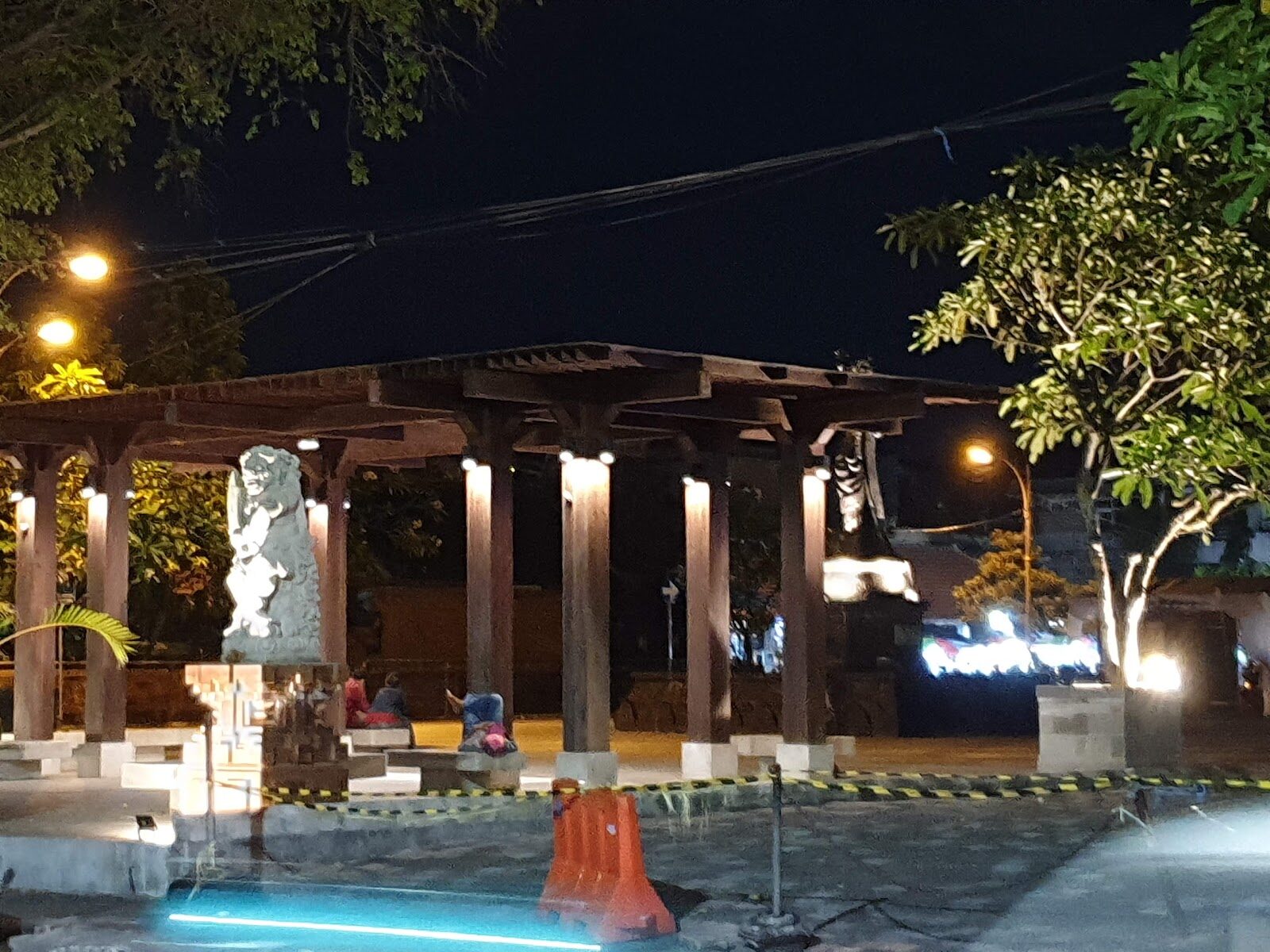 An ordinary Bali street after dark — statues, streetlamps, scooters. The after-hours economy hides inside exactly this kind of everyday backdrop.
